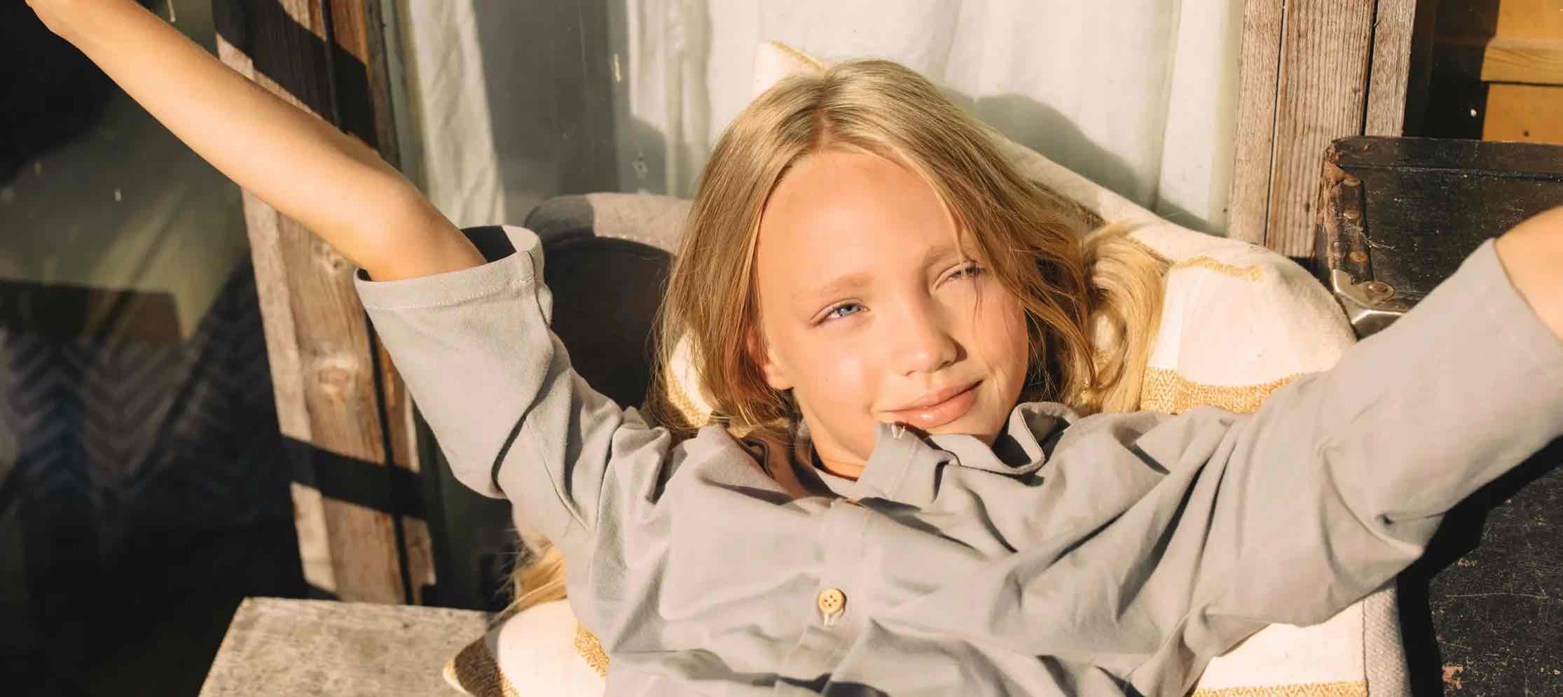 Mädchen liegt auf dem Balkon und streckt seine Arme aus