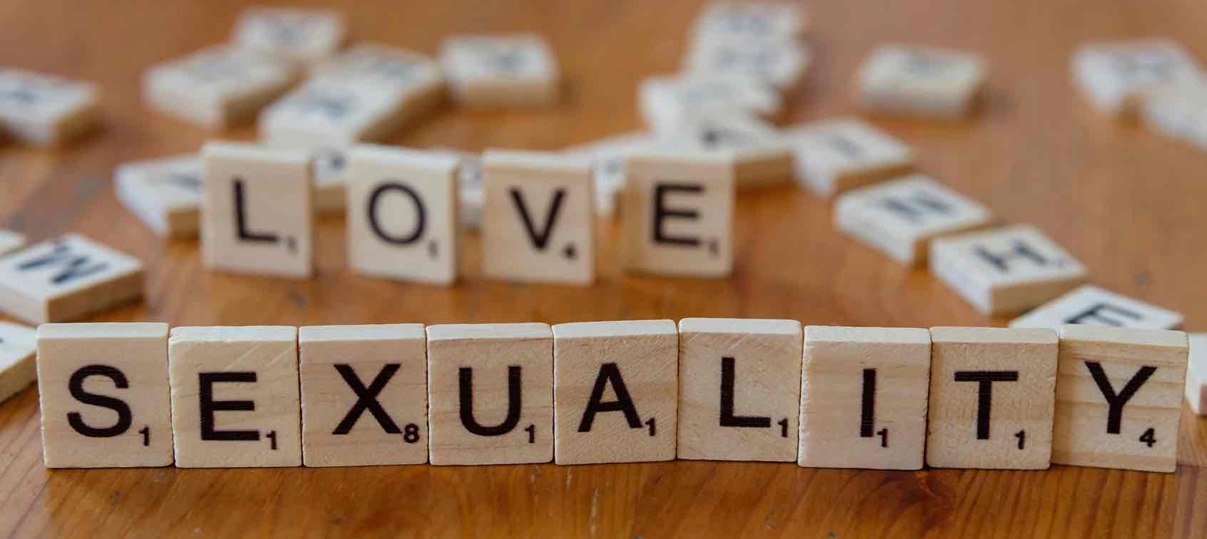 Pubertät bei Jungen Scrabblebuchstaben die im Hintergrund "LOVE" und im Vordergrund "SEXUALITY" zeigen