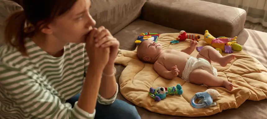 Bedürfnisorientierte Erziehung Kritik Mutter sitzt nachdenklich neben ihrem Baby