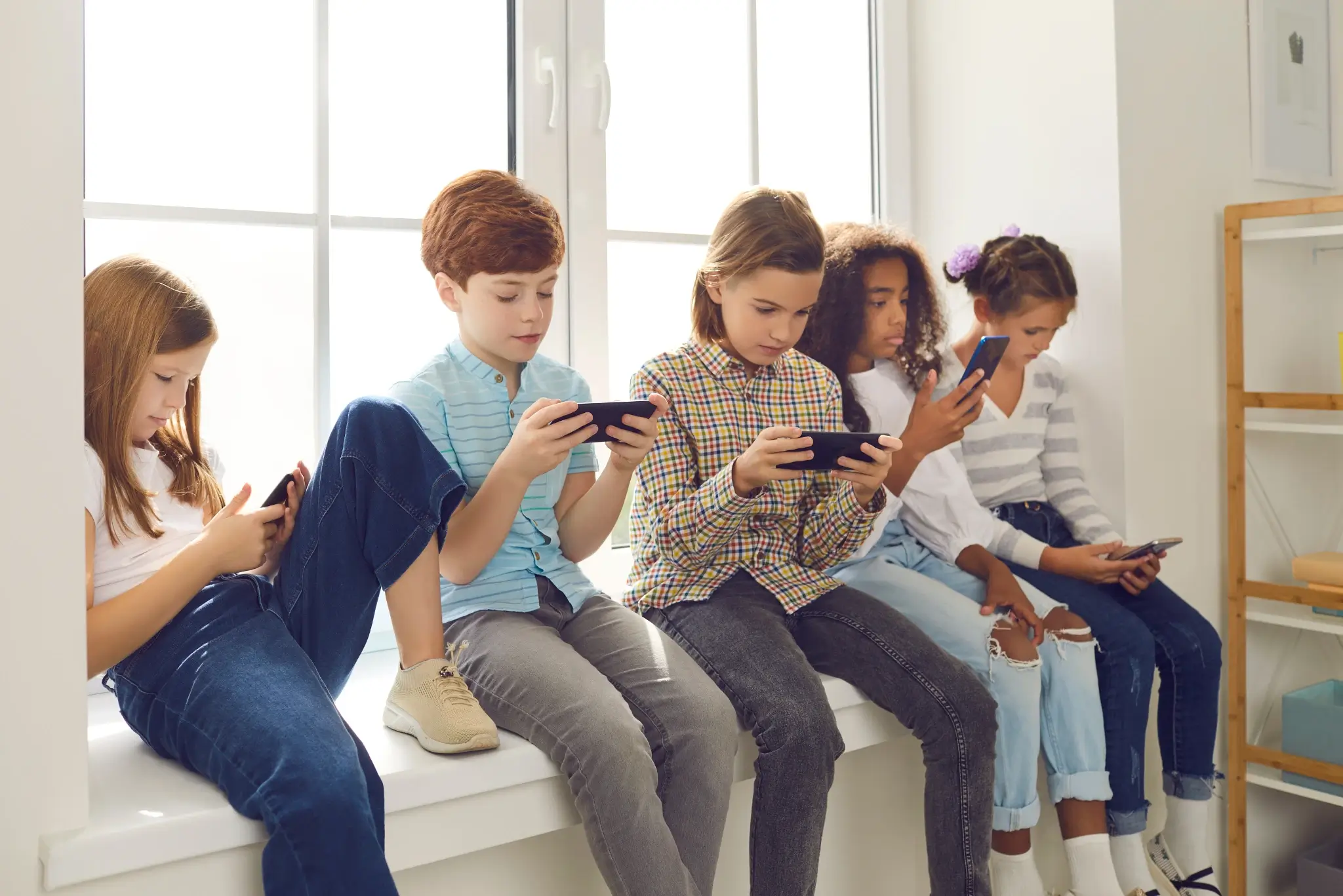 Klassenfahrt Handy Kinder sitzen nebeneinander am Handx