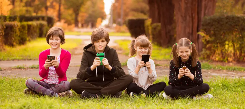 Kinder sehen lächend in ihr Handy